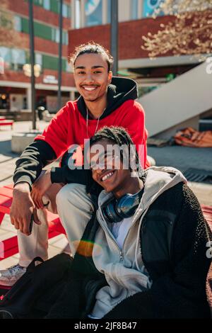 Portrait of happy man sitting with smiling friend on bench Stock Photo