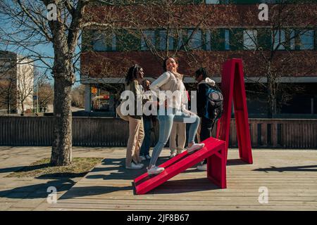Side view of young woman posing by friends on sunny day Stock Photo