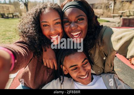 Portrait of happy young women taking selfie with male friend on sunny day Stock Photo