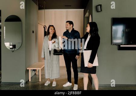 Real estate agent showing house to smiling couple Stock Photo