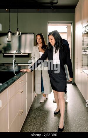 Real estate agent showing kitchen island to couple at home Stock Photo