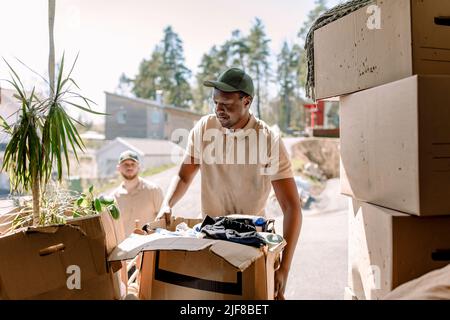 Movers picking cardboard boxes from delivery truck Stock Photo