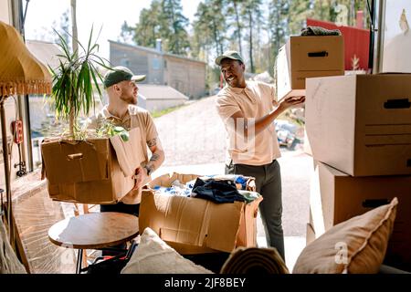 Multiracial movers unloading boxes from delivery truck Stock Photo