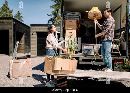 Couple unloading cardboard boxes from truck during sunny day Stock Photo