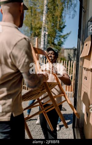 Movers unloading chair from truck on sunny day Stock Photo