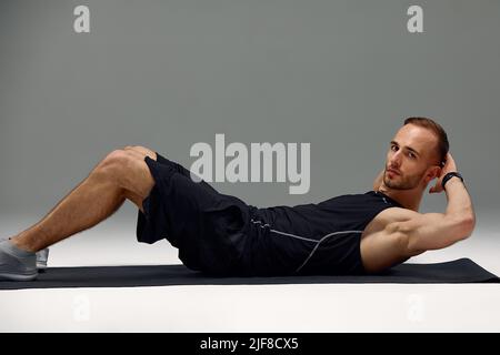 https://l450v.alamy.com/450v/2jf8cx5/male-morning-workout-sporty-man-doing-sit-ups-abs-exercise-on-gymnastics-mat-training-and-working-out-fitness-lifestyle-motivation-stay-fit-concept-2jf8cx5.jpg