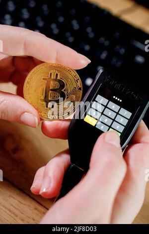 Close up womans hand holding bitcoin and cryptocurrencey hardware cold wallet on keybord background. Secure cryptocurrency storage. Stock Photo