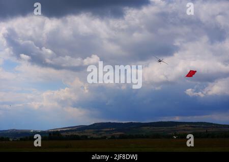 Model plane towing Turkish flag in airshow flying within dark clouds Stock Photo