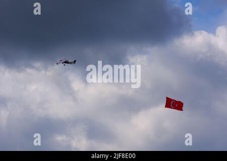 Model plane towing Turkish flag in airshow flying within dark clouds Stock Photo