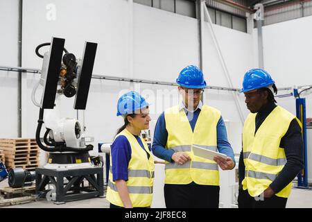 Industrial engineers working with automated arm robot inside AI robotic production factory - New technology concept - Focus on senior woman face Stock Photo