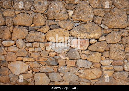 An old stone wall made using different types of stone. Stone wall background. Closeup and front view. Stock Photo