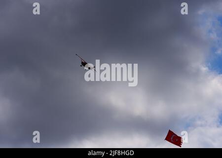 Model plane towing Turkish flag in airshow flying within dark clouds Stock Photo