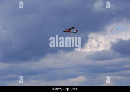 Small airplane flying within dark clouds Stock Photo