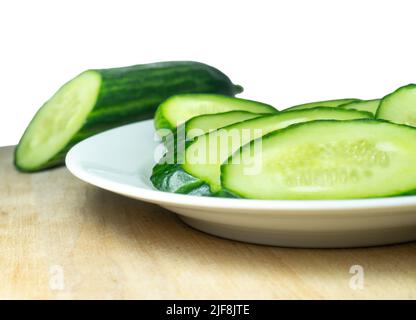 A smooth, medium-sized cucumber cut into slices. Cucumber on a plate. Vegetable isolate. Fresh ripe vegetable before cooking dinner. Stock Photo