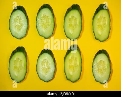 A smooth, medium-sized cucumber cut into slices. Cucumber on a cutting board. Vegetable isolate. Background of slices Stock Photo