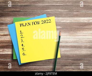 Writing note showing plan for 2022 on wood table background. top view with copy space.Goals ideas and resolutions for 2022 Stock Photo