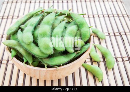 Fresh green soybeans in wooden bowl on wooden background. Stock Photo