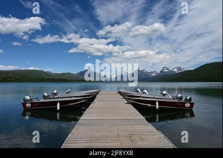 Apgar Village, Montana - 6-23-2022 - Rental outboard boats tied to dock in Lake McDonald in Glacier National Park under beautiful summer cloudscape. Stock Photo