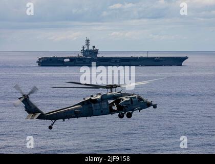 220628-N-YD731-1525 ATLANTIC OCEAN (June 28, 2022) An MH-60S Knighthawk Helicopter, attached to Helicopter Sea Combat Squadron (HSC) 5, hovers as the Nimitz-class aircraft carrier USS George H.W. Bush (CVN 77) transits the Atlantic Ocean, June 28, 2022. The George H.W. Bush Carrier Strike Group (CSG) is underway completing a certification exercise to increase U.S. and allied interoperability and warfighting capability before a future deployment. The George H.W. Bush CSG is an integrated combat weapons system that delivers superior combat capability to deter, and if necessary, defeat America's Stock Photo