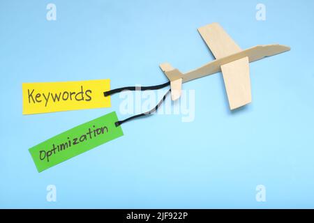 Keyword and Search Engine Optimization or SEO importance and key for success concept in business marketing. Airplane model carrying paper banner. Stock Photo