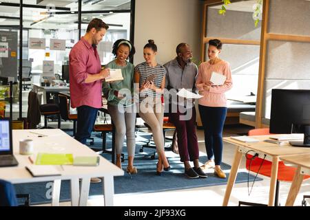 Multiracial business colleagues with documents discussing strategy in creative office Stock Photo