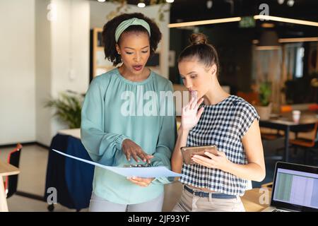 Multiracial female colleagues discussing over file in creative office Stock Photo