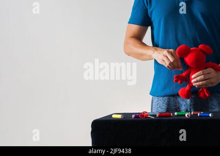 Man in non-stereotypical role doing housework sewing the doll for children on white background. Stock Photo