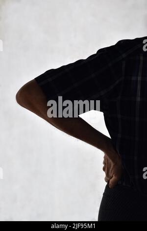 Partial silhouette image of Asian elder man suffering from right sided low back and loin pain. It can be caused by mechanical or pathological process. Stock Photo