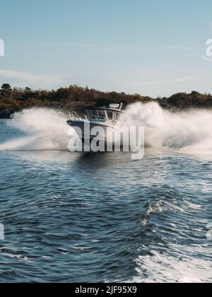 Speedboat in navigation goes on the waves in deep blue water, sea view. Stock Photo