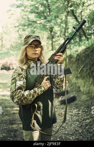 Portrait of a Ukrainian military woman with a machine gun in the hands ...