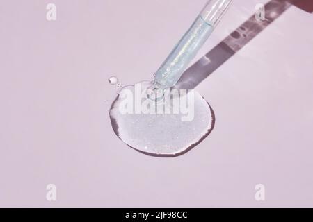 A drop of cosmetic gel or face serum oil falls from the pipette. Cosmetic product texture Stock Photo