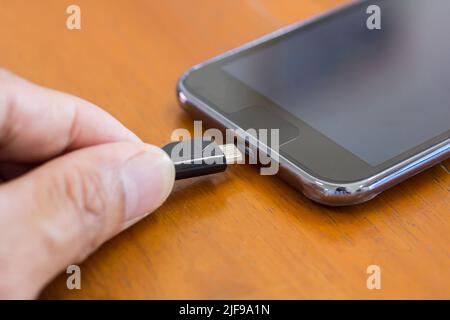 Close up hands plugging a charger in a smart phone in the bedroom at home Stock Photo