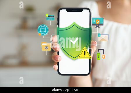 Young woman holding mobile phone, closeup. Antivirus concept Stock Photo