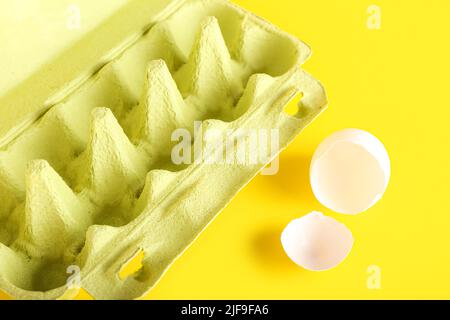 Cardboard holder with broken egg shell on yellow background Stock Photo