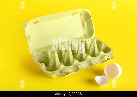 Cardboard holder with broken egg shell on yellow background Stock Photo