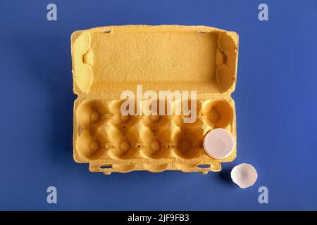 Cardboard holder with broken egg shell on blue background Stock Photo