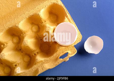 Cardboard holder with broken egg shell on blue background Stock Photo