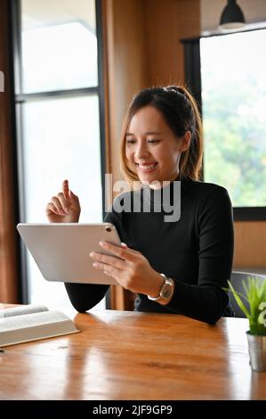 Portrait of a beautiful young asian woman or female freelance designer using portable digital tablet touchpad at her desk. Stock Photo