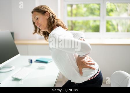 Woman On Sofa Suffering From Backpain At Home Stock Photo