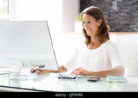 Woman In Office Using Business Computer At Desk Stock Photo