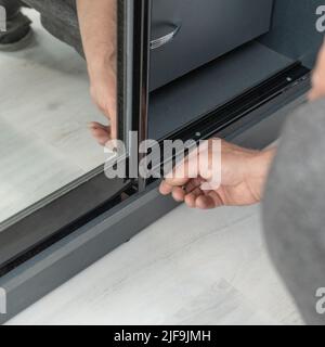 Installation of a case by means of the screw, the detailed plan of work of the master with the hexagonal screw, screwing of a door to a case. Stock Photo