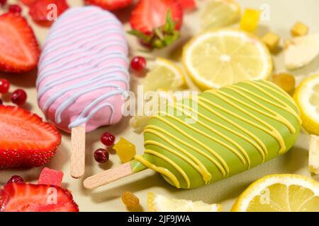 Two ice creams on a sticks - strawberry and lemon on a beige background. Summer fruit desserts. Stock Photo