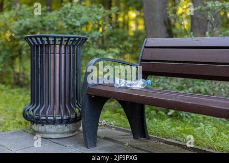 a crumpled plastic bottle lies on an empty park bench. High quality photo Stock Photo