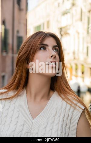 portrait of young redhead woman looking away on blurred background in Venice Stock Photo