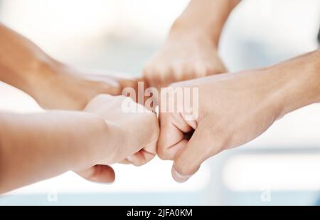 Closeup of diverse group of people making fists in a circle to express unity, support and solidarity. Hands of multiracial community greeting with Stock Photo