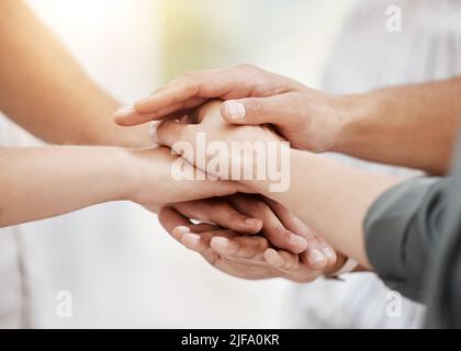 Closeup of diverse group of people stacking hands together in a pile to express unity, support and trust. Multiracial community huddled in a circle to Stock Photo