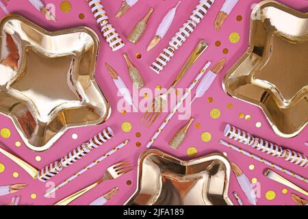 Party flat lay with golden and white decoration like plates, confetti and feathers on pink background Stock Photo