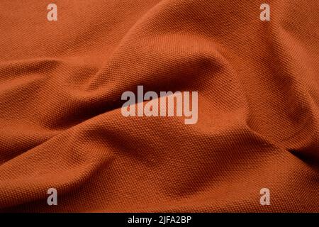 Textured fabric background. An earthy orange colour, ruched fabric. Stock Photo