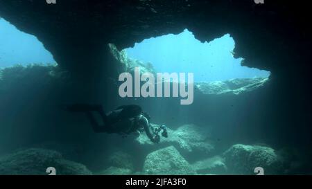 Scuba diver photographer swim in the cave. Cave diving in Mediterranean Sea, Cyprus Stock Photo