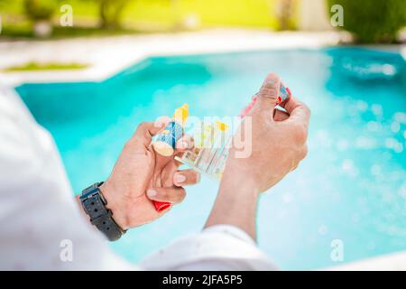 Hand holding a pool ph and chlorine tester, Hand holding Water Test Kit on blurred pool background, Person holding complete water test kit with Stock Photo